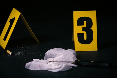 Photo of Stub, knife and bloody napkin on black slate table at crime scene