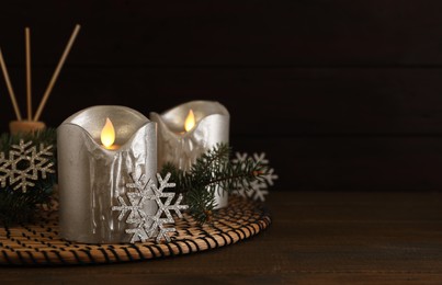 Decorative LED candles and snowflakes on wooden table, space for text