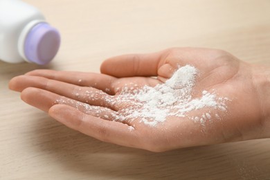 Photo of Woman with dusting powder at wooden table, closeup