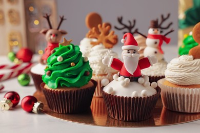 Different beautiful Christmas cupcakes and baubles on white table