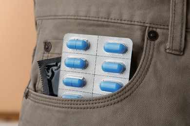 Pants with pills and condom in pocket, closeup. Potency problem