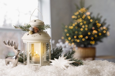 Composition with Christmas lantern on table in decorated room, space for text