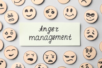 Words Anger Management and many faces with different emotions on grey background, flat lay