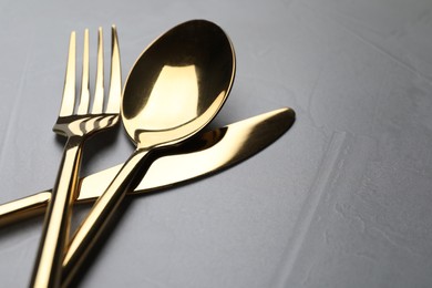 Photo of Golden cutlery on grey table, closeup. Space for text