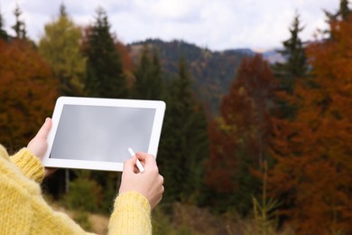 Woman drawing with graphic tablet in mountains on autumn day, closeup