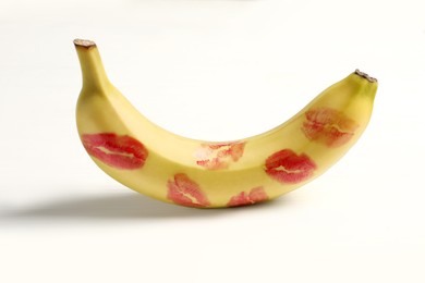 Banana covered with red lipstick marks on white wooden table. Potency concept