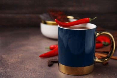 Photo of Cup of hot chocolate with chili pepper on grey table. Space for text