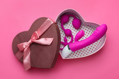 Gift box with sex toys on pink background, top view