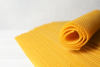 Photo of Natural organic beeswax sheets on white wooden table, closeup. Space for text