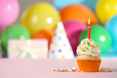 Birthday cupcake with candle on pink table against blurred background. Space for text