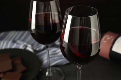 Glasses of red wine with chocolate on grey table, closeup