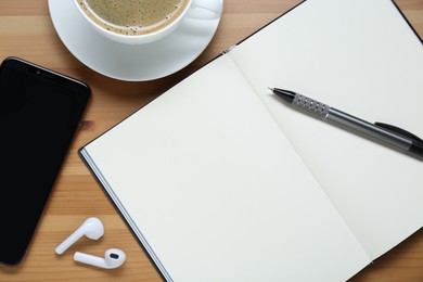 Empty notebook, smartphone, coffee and stationery on wooden table, flat lay