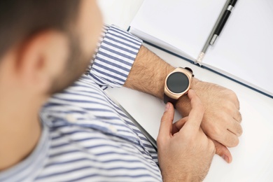 Man checking smart watch at desk in office, closeup