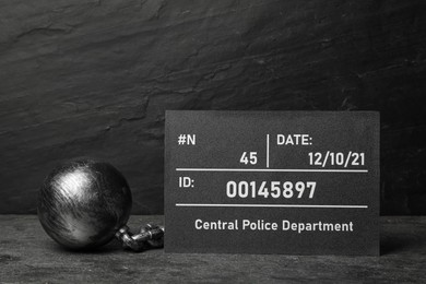 Metal ball with chain and mugshot letter board on grey table