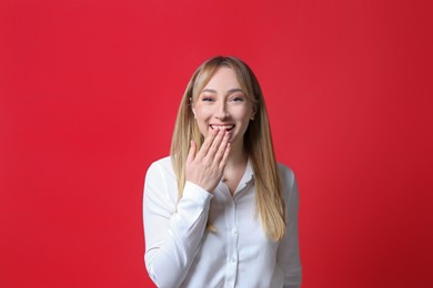 Beautiful young woman laughing on red background. Funny joke