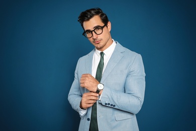 Portrait of handsome young businessman wearing glasses on blue background