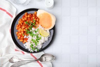 Delicious chickpea curry with rice served on white tiled table, flat lay. Space for text