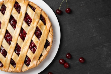 Delicious fresh pie and cherries on black slate table, flat lay. Space for text