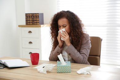 Sick African-American woman at workplace. Influenza virus