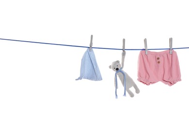 Baby clothes and toy bear drying on laundry line against white background