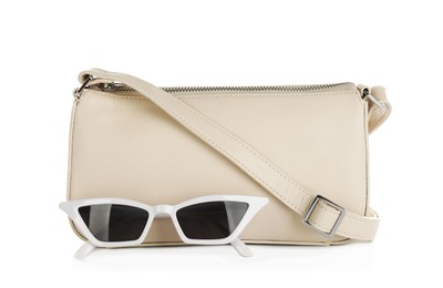 Women's leather bag and sunglasses on white background