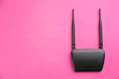 Modern Wi-Fi router on pink background, top view. Space for text