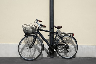 Vintage bicycle with basket locked to street post outdoors