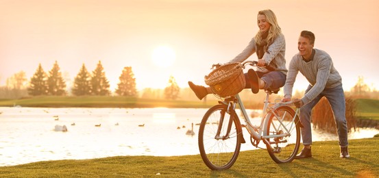Image of Happy young couple with bicycle having fun outdoors, space for text. Banner design