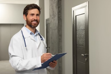 Doctor in white coat with stethoscope and clipboard indoors. Space for text
