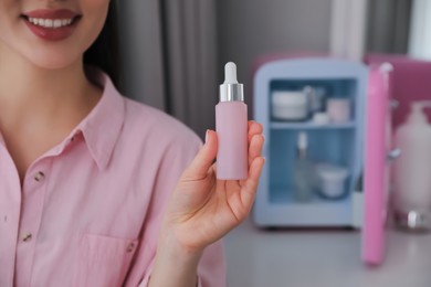 Woman with cosmetic product out of mini refrigerator indoors, closeup