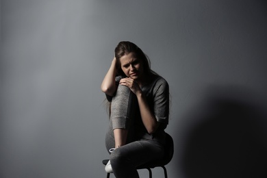 Depressed young woman on gray background