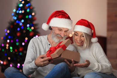 Happy couple opening Christmas gift at home