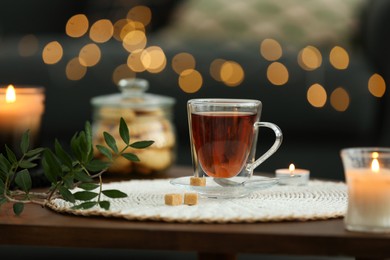Photo of Tea, cookies and decorative elements on wooden table against blurred lights indoors