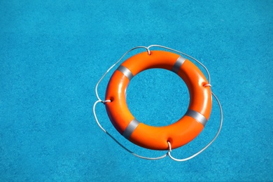 Bright orange inflatable ring floating in swimming pool, top view