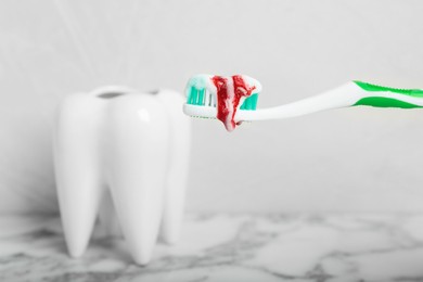 Photo of Toothbrush with paste and blood near tooth model, space for text. Gum inflammation
