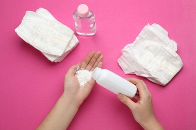 Woman applying dusting powder on pink background, top view