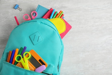 Stylish backpack with different school stationary on white table, top view. Space for text
