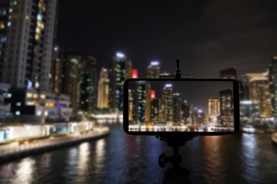 DUBAI, UNITED ARAB EMIRATES - NOVEMBER 03, 2018: Night cityscape of marina district, blurred view. Taking photo with smartphone mounted on tripod