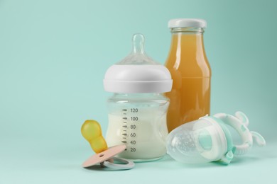 Photo of Milk, juice, pacifier and nibbler on light blue background. Baby nutrition