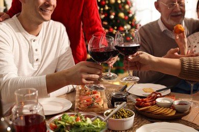 Happy family clinking glasses of wine at festive dinner, focus on hands. Christmas celebration