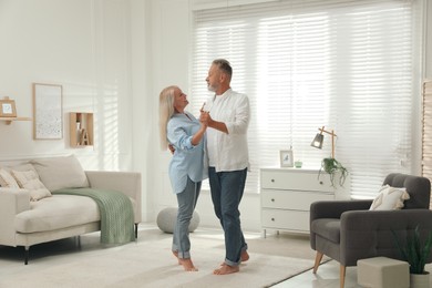Happy senior couple dancing together in living room