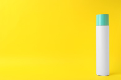 Photo of Bottle of dry shampoo on yellow background. Space for text