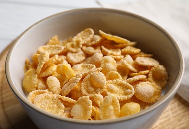 Tasty cornflakes with milk in bowl on table, closeup