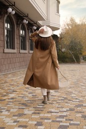 Young woman wearing stylish autumn clothes on city street, back view