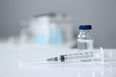 Syringe and vial on white table. Space for text