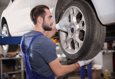 Young mechanic changing wheel at tire service