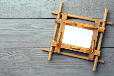 Empty bamboo frame on grey wooden background, top view. Space for text