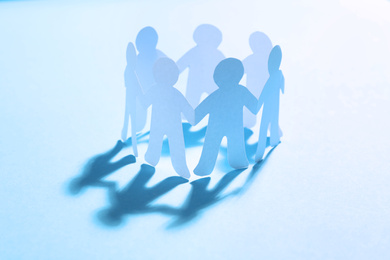 Paper people chain making circle on light blue background. Unity concept