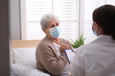 Photo of Doctor examining senior woman with protective mask at nursing home