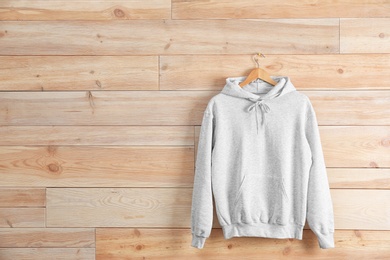 New hoodie sweater with hanger on wooden wall. Mockup for design